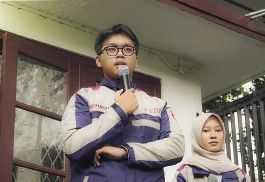 A finalist speaking into a microphone at the GEMASTIK XVIII send-off