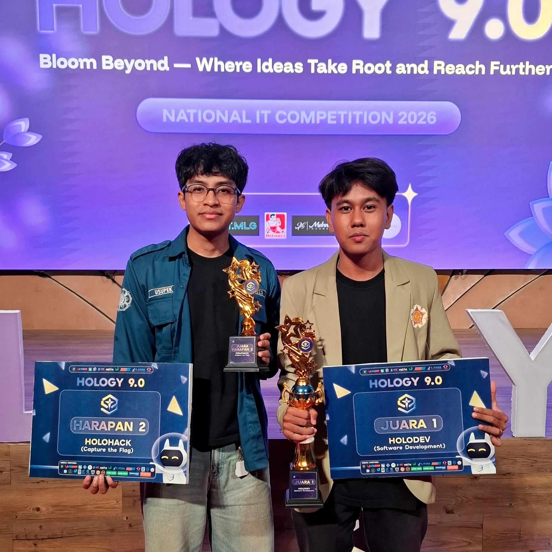Azril and a school friend, each holding a HOLOGY 9.0 trophy
