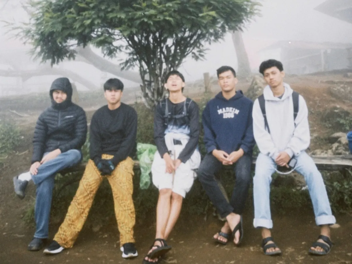 Five high-school friends sitting under a tree on a foggy hill